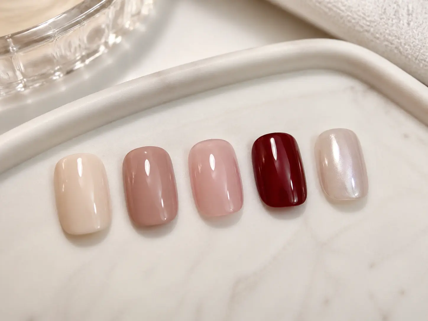 Short manicure sample tips showing classy color options in milky beige, rosy nude, sheer pink, cherry, and pearl chrome.